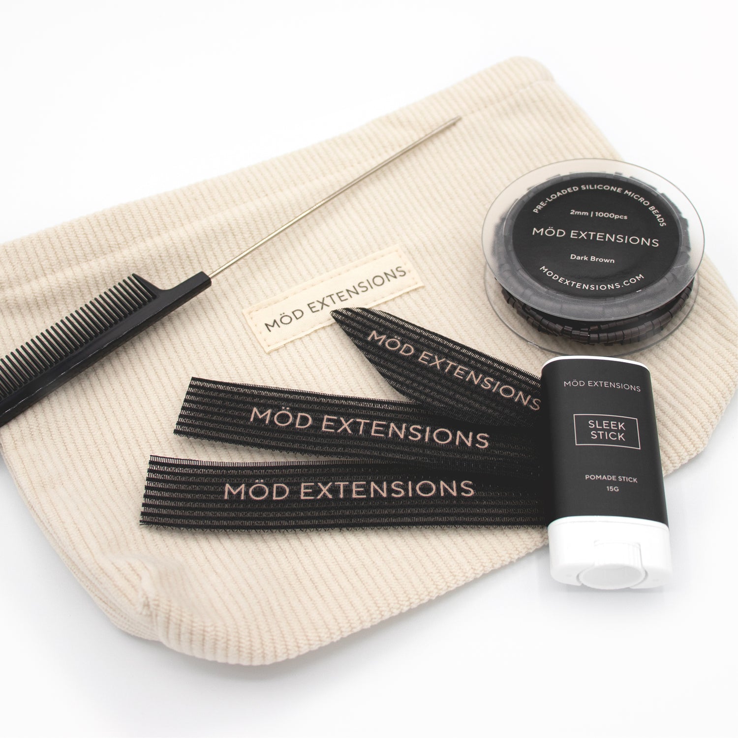 Mod Extensions hair product set including Sleek Stick, Metal Tail Comb, Hair Grippers and Beads on a beige pouch.